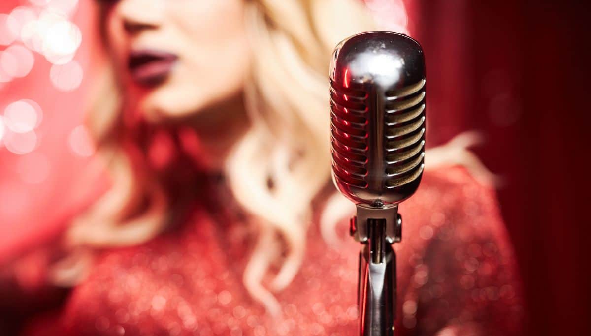 A drag queen singing in a microphone.