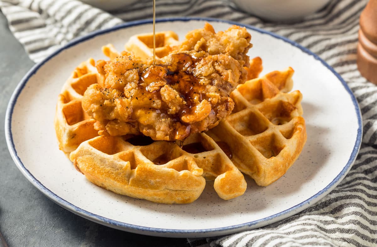 Chicken and waffles with syrup drizzled on top.