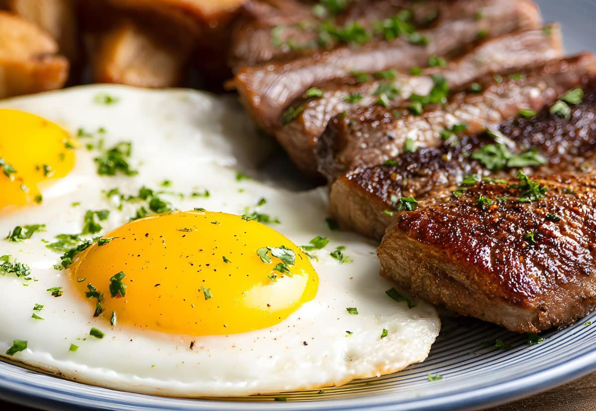 Steak and eggs benedict with a side of breakfast potatoes.